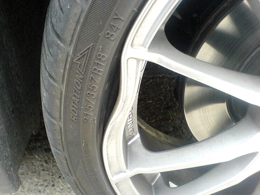 Roda amassada sendo verificada em bancada de oficina